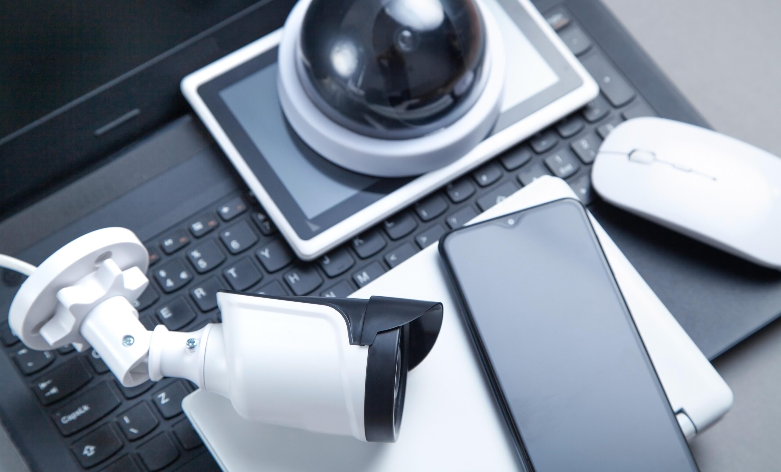 Laptop keyboard, smartphone, security camera, tablet. Security